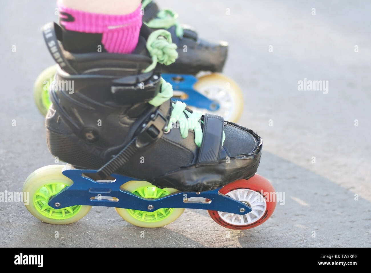 Patineur rouleau prêt à démarrer. Travail réel rouleaux battues pour inline skating et de slalom. Chaussures noires sur trois roues avec châssis bleu roue colorée Banque D'Images