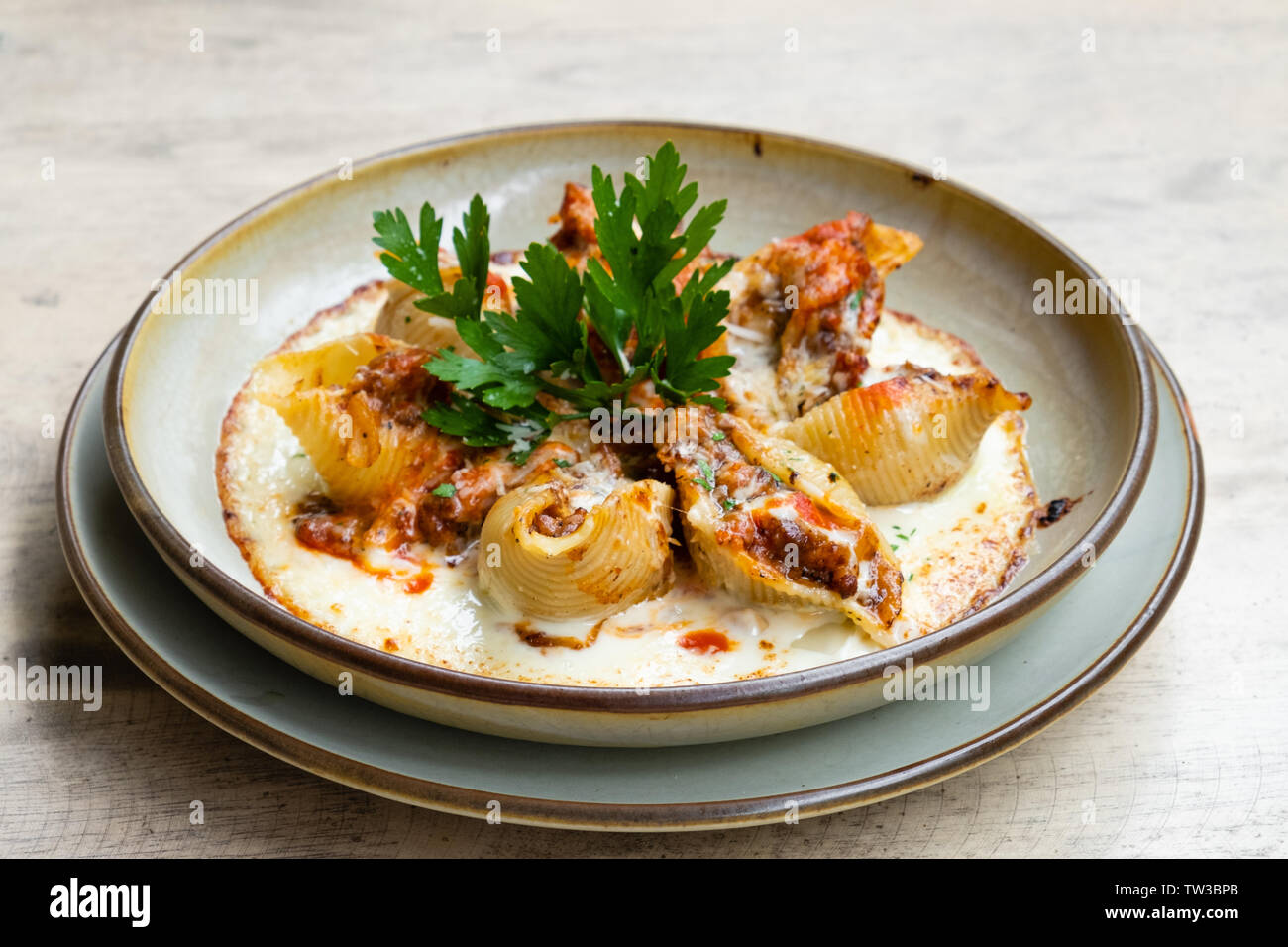 Près d'un italien frais maison pâtes farcies de porc ragoût de boeuf conchiglioni avec ragu bolognese sauce tomate avec fromage à la crème le persil herbes tra Banque D'Images