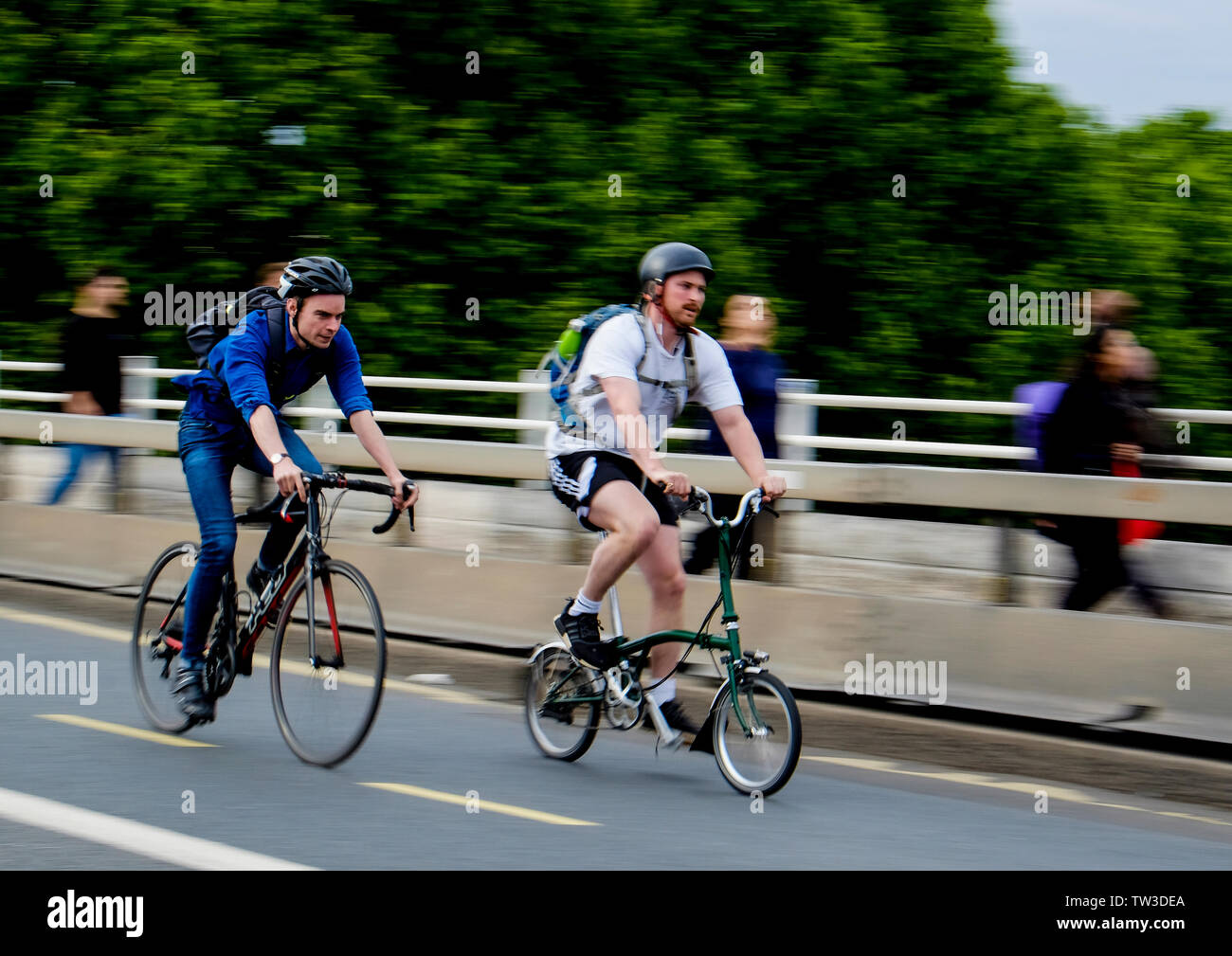Motion Blur capture d'un homme sur un vélo de course cycliste rattrape un autre sur un vélo pliant sur Waterloo Bridge, Londres Banque D'Images