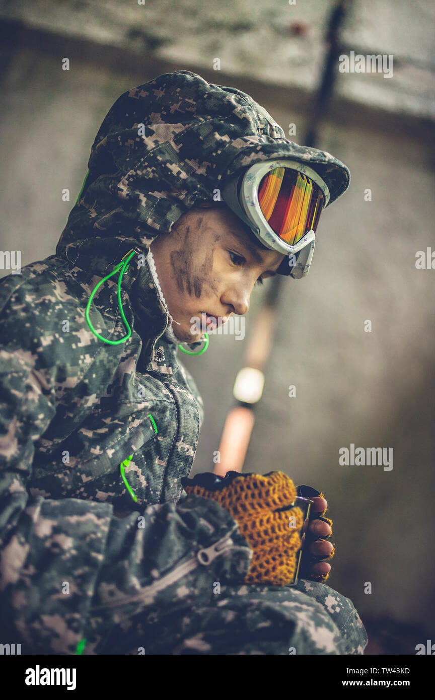 Petite fille en tenue de camouflage se cache dans un bâtiment détruit. Photoset basé sur le jeu de Tchernobyl. Zone d'exclusion. Banque D'Images