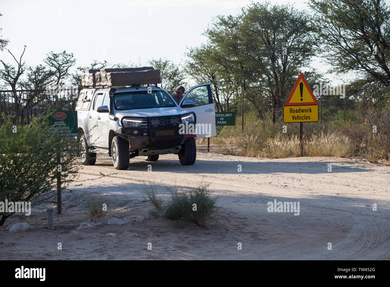 White 4x4 véhicule de camping par voie terrestre avec un homme à obtenir à l'entrée principale à Nossob rest camp, Kgalagadi Transfrontier National Park Banque D'Images