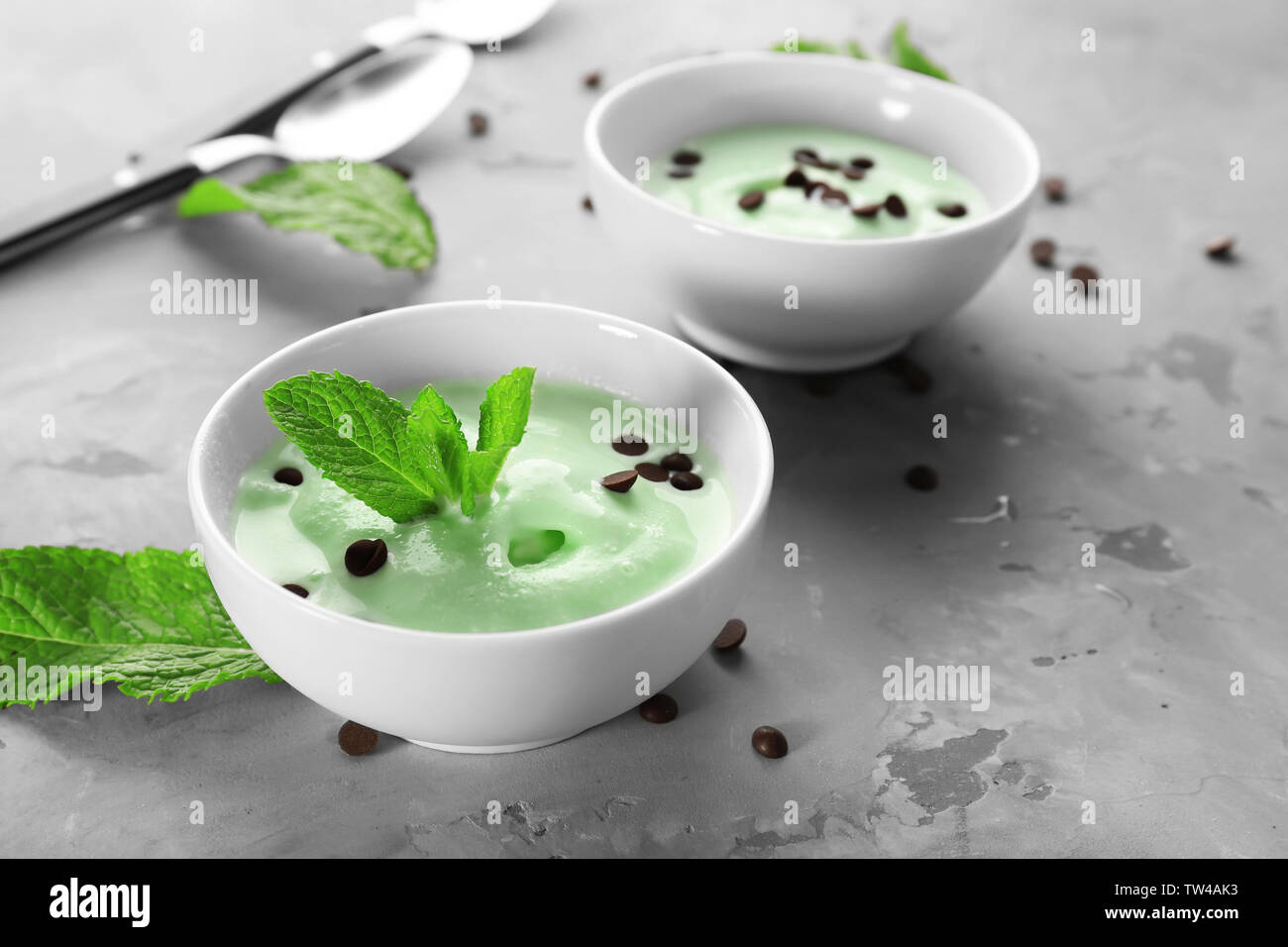 Délicieuse menthe avec bols de crème glacée aux pépites de chocolat et les feuilles fraîches sur la table gris Banque D'Images