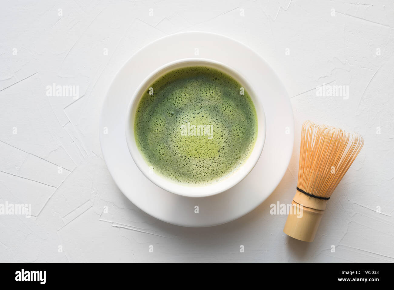 Traditionnelle cérémonie du thé vert matcha dans un bol et fouetter en bambou sur table en béton blanc. Vue d'en haut. Banque D'Images