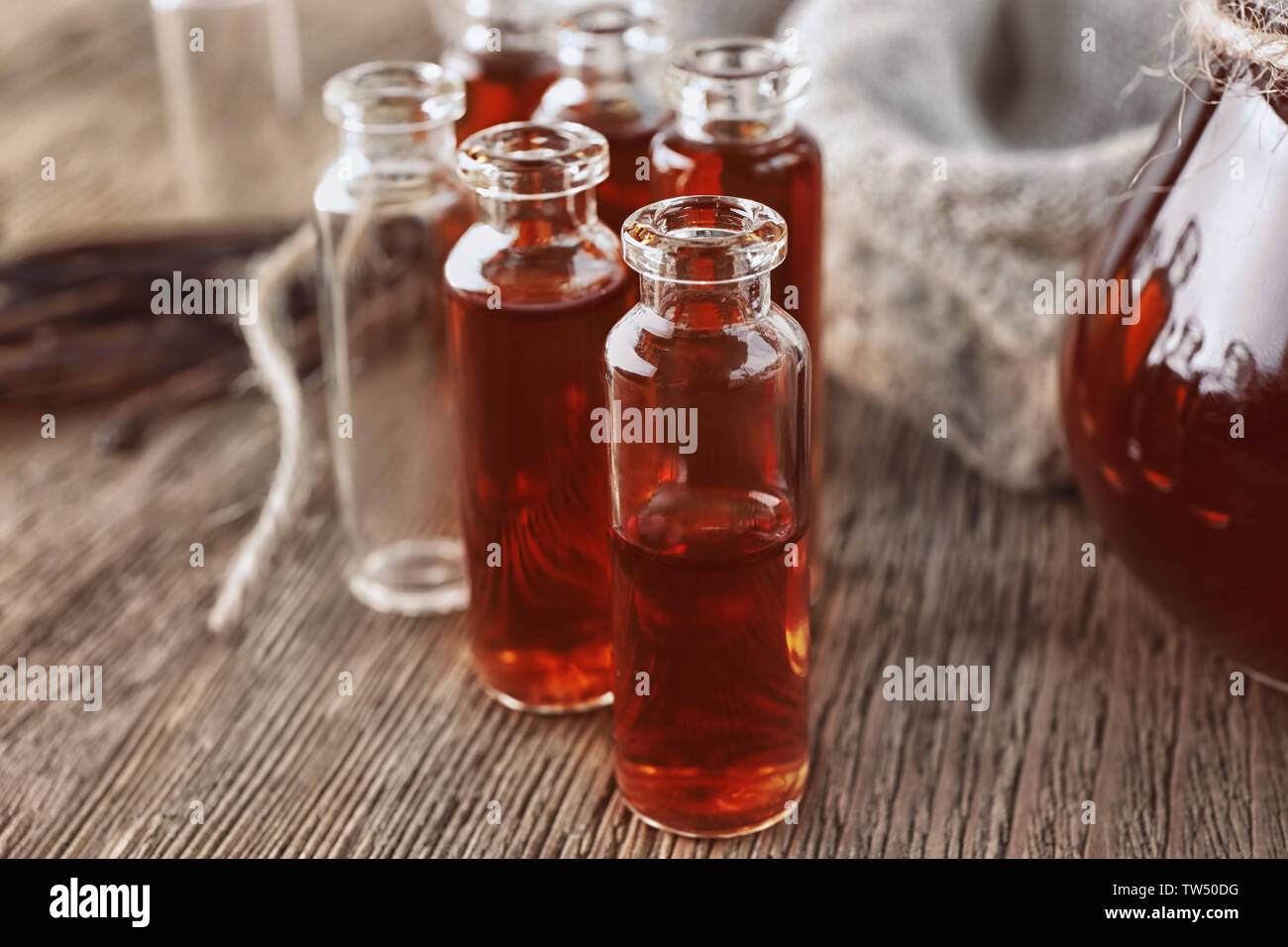 Petites bouteilles avec de l'extrait de vanille aromatiques sur table Banque D'Images