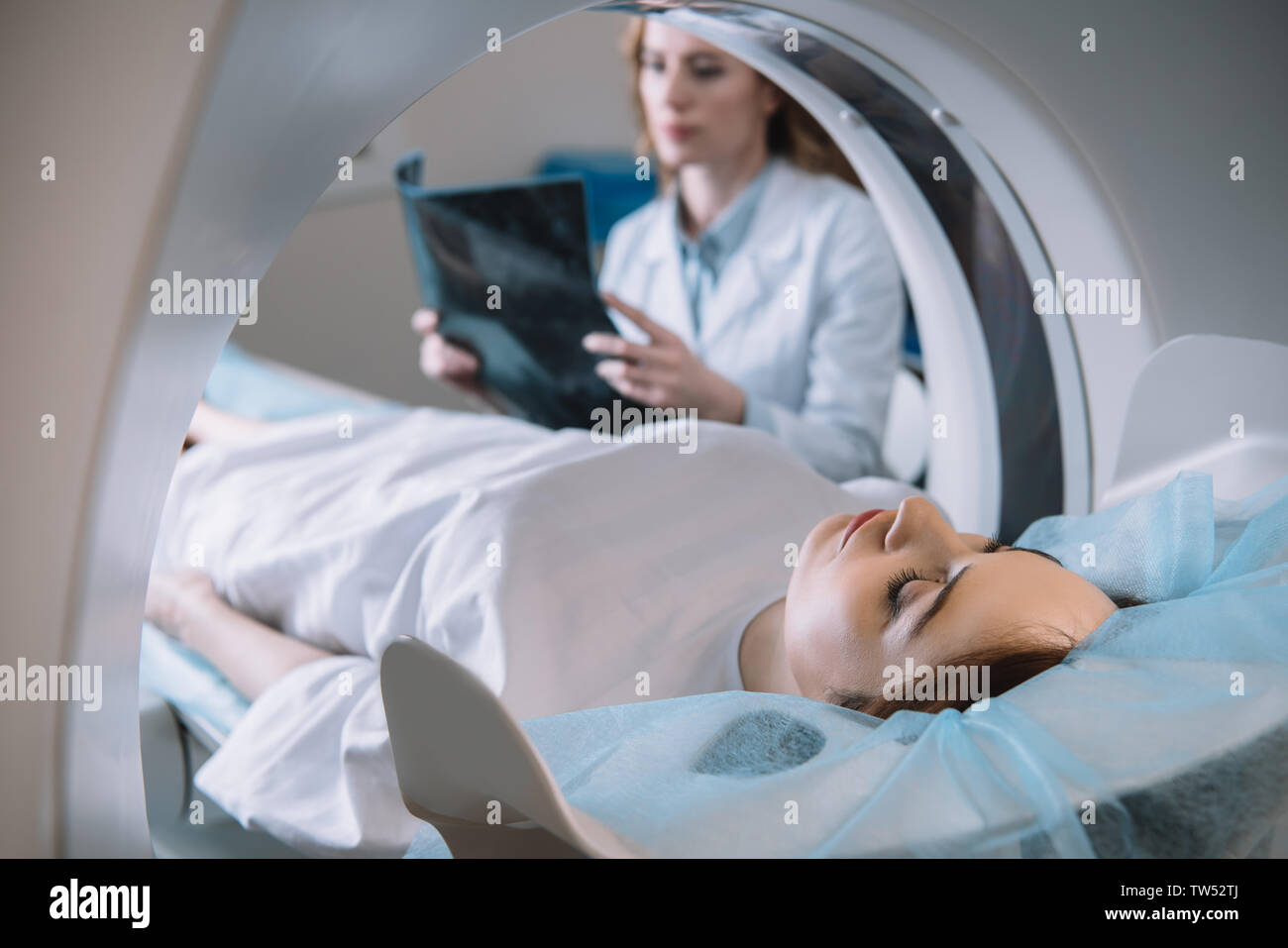 Focus sélectif de radiologue holding x-ray alors que le diagnostic patient couché sur le lit du scanner ct pendant le diagnostic Banque D'Images