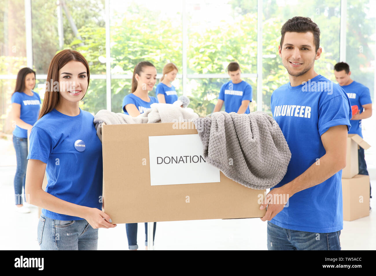 Deux jeunes bénévoles heureux holding box avec des dons à l'intérieur Banque D'Images