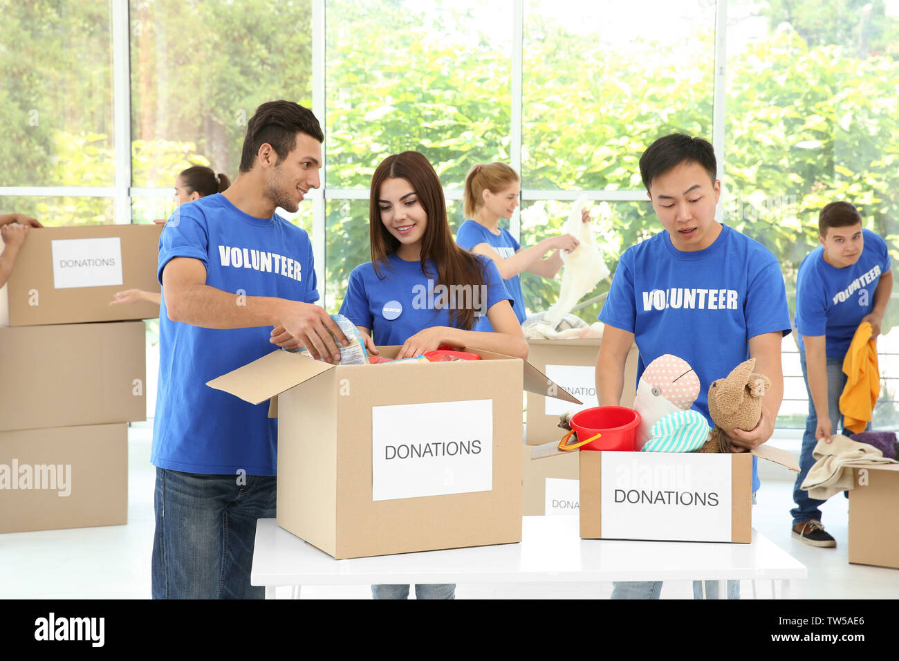 Équipe de jeunes bénévoles à la collecte de dons dans des boîtes de carton à l'intérieur Banque D'Images