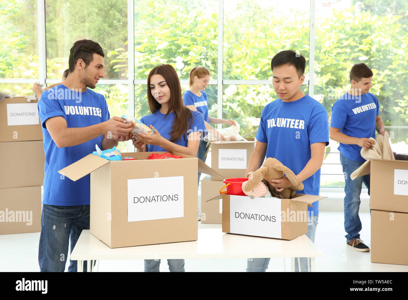 Équipe de jeunes bénévoles à la collecte de dons dans des boîtes de carton à l'intérieur Banque D'Images