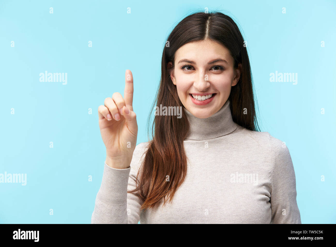 Belle jeune femme de race blanche en appuyant sur un bouton virtuel, smiling at camera, isolé sur fond bleu Banque D'Images