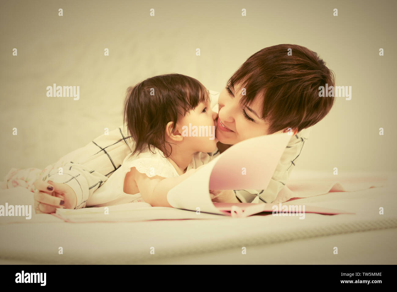 Heureux jeune mère et little baby girl reading a book on bed Banque D'Images