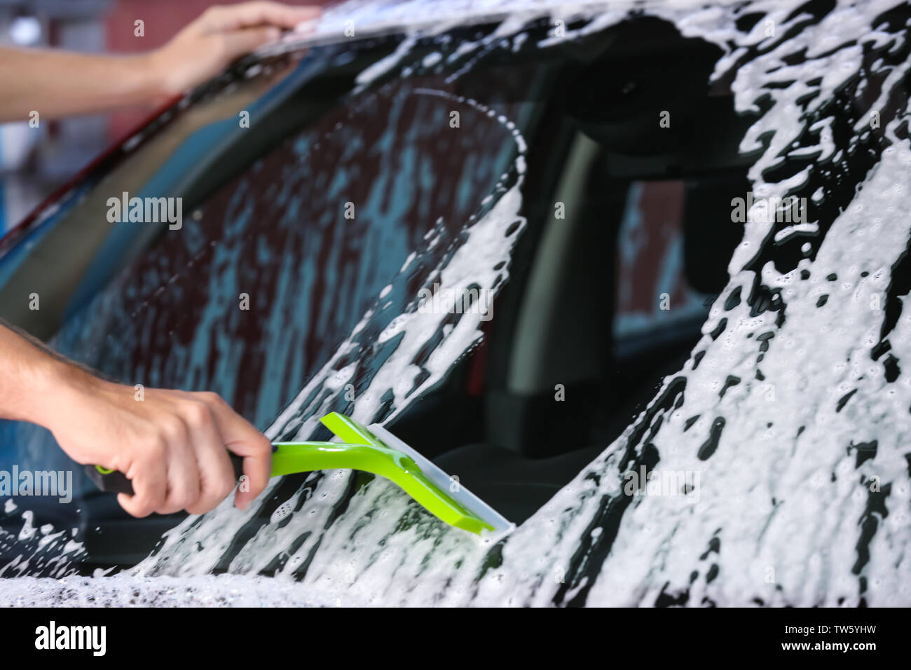 L'homme à la raclette de pare-brise automobile nettoyage au lavage de voiture Banque D'Images