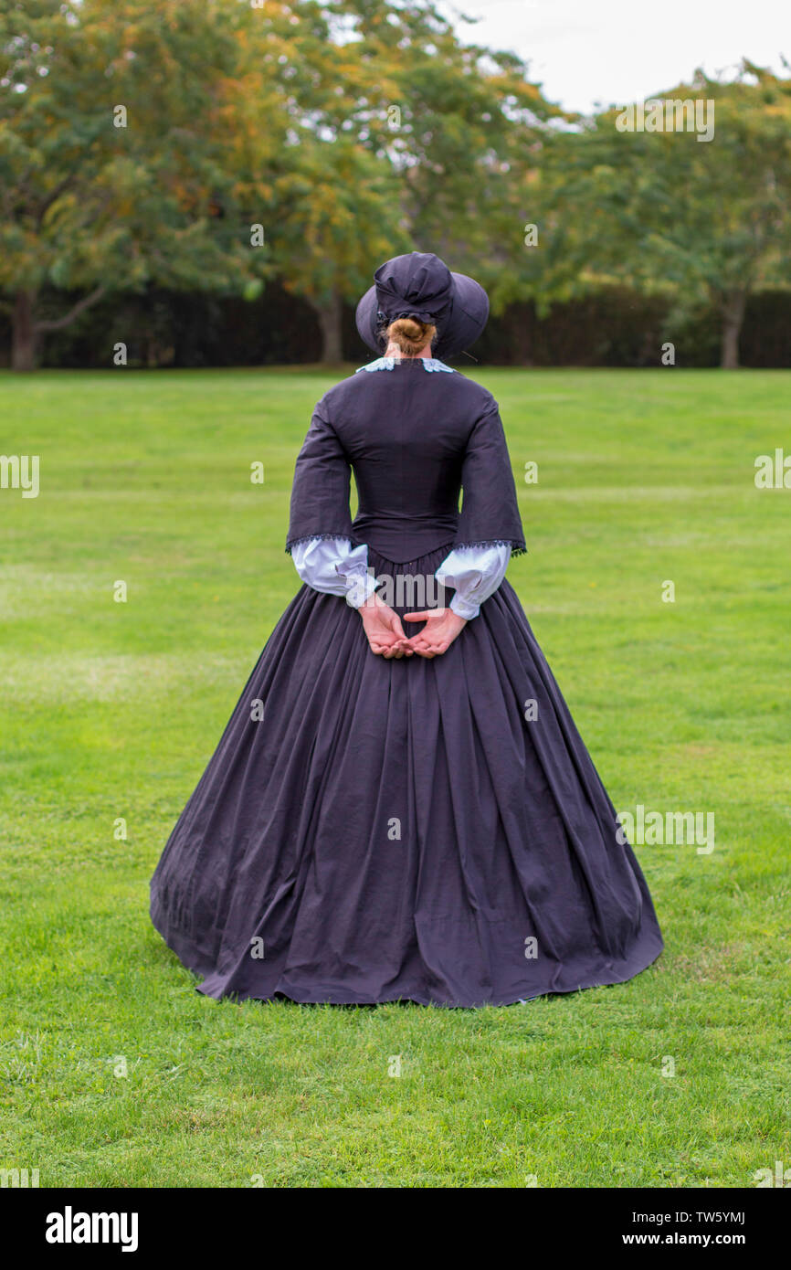 Victorian woman in black band walking in garden Banque D'Images