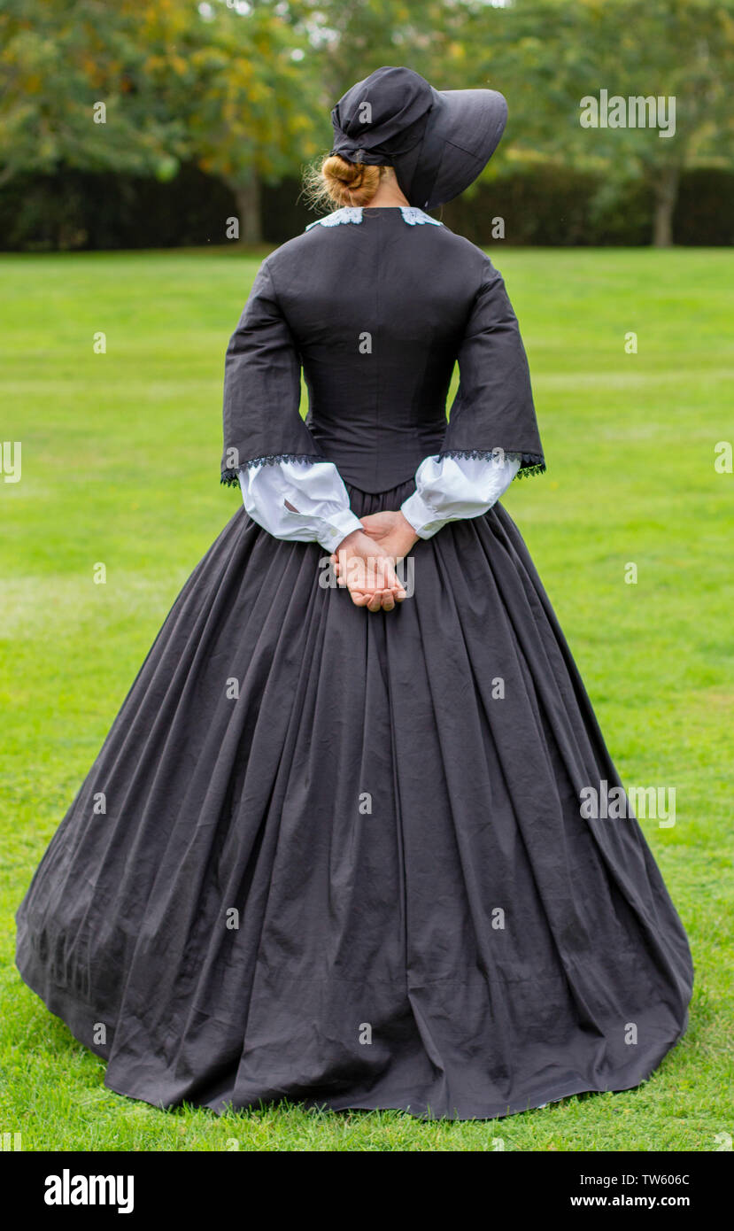 Victorian woman in black band walking in garden Banque D'Images