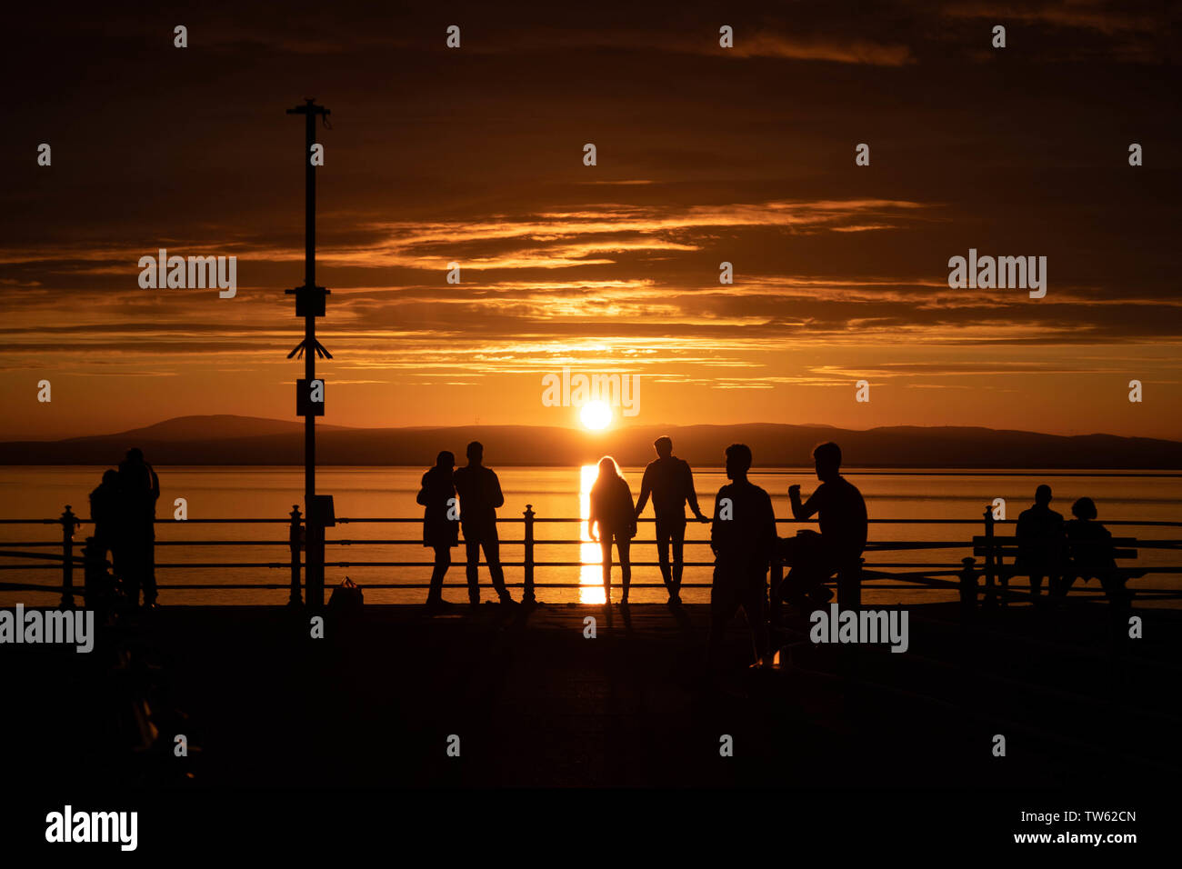 Point de Trafalgar, Morecambe, Lancashire, Royaume-Uni, le 18 juin 2019 visiteurs regardant le coucher du soleil à partir de la fin de la jetée en pierre connu comme point de Trafalgar. Credit : photographier_Nord/Alamy Live News Banque D'Images