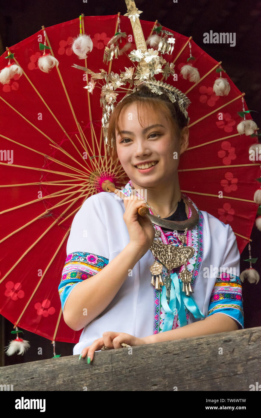 Dong girl en costume traditionnel avec un parapluie rouge, province du Hunan, Chine Banque D'Images