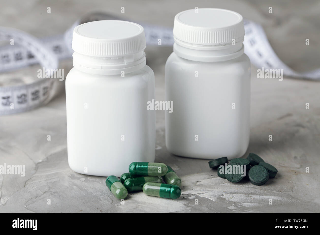 Les contenants avec des capsules et des comprimés de spiruline sur table Banque D'Images
