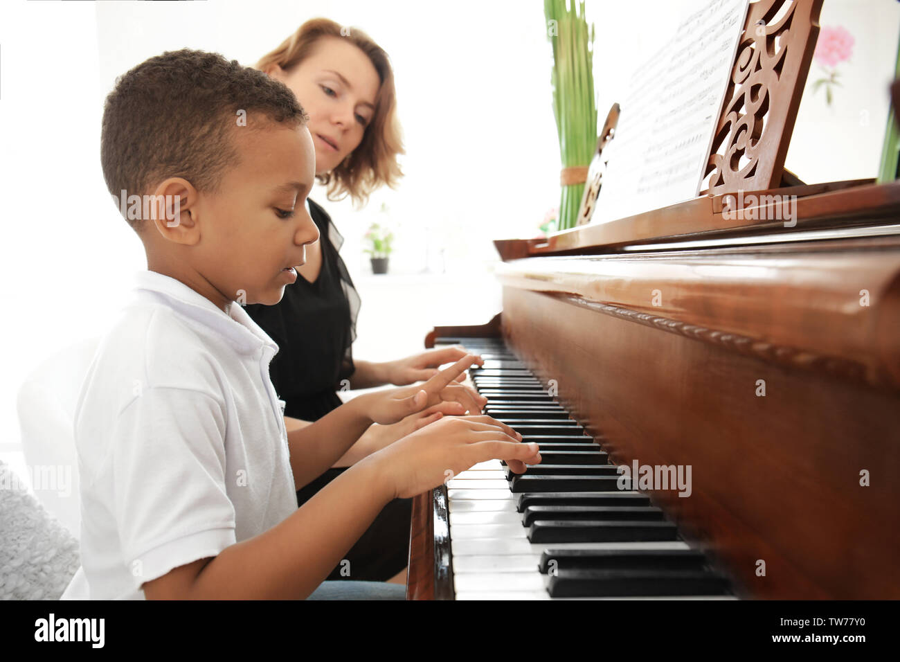 Garçon afro-américain avec l'enseignant Apprendre à jouer du piano à l'intérieur Banque D'Images