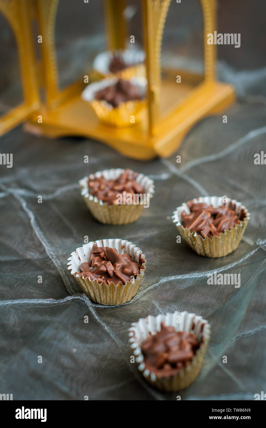 En Amandes enrobées de chocolat en papier doré avec golden phare en arrière-plan. Banque D'Images