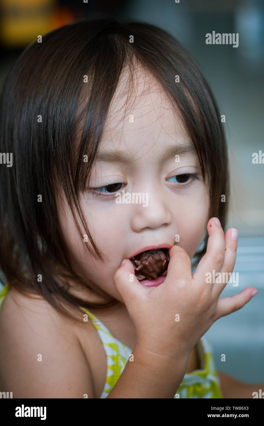 Portrait of asian little girl avec une bouche pleine d'en-cas. Banque D'Images