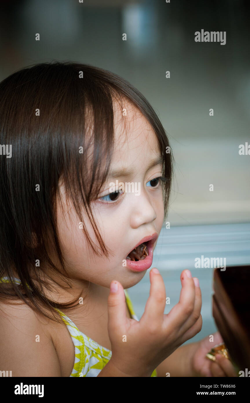 Portrait of asian little girl avec une bouche pleine d'en-cas. Banque D'Images