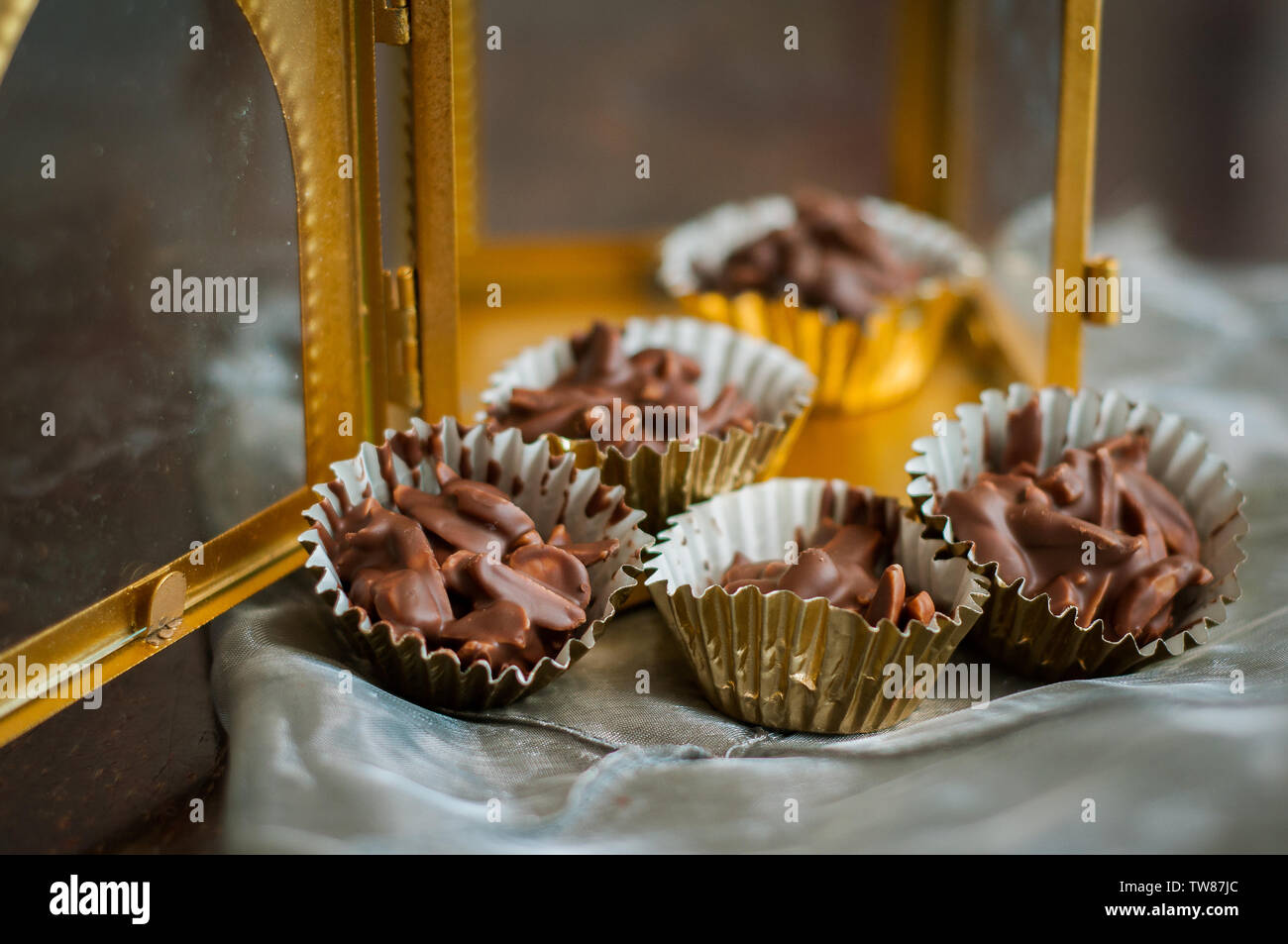 En Amandes enrobées de chocolat en papier doré avec golden phare en arrière-plan. Banque D'Images