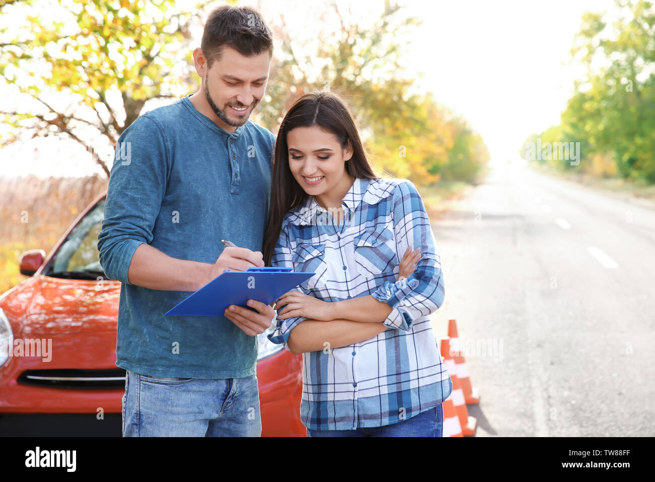 Jeune femme et d'instructeur de conduite debout près de voiture Banque D'Images