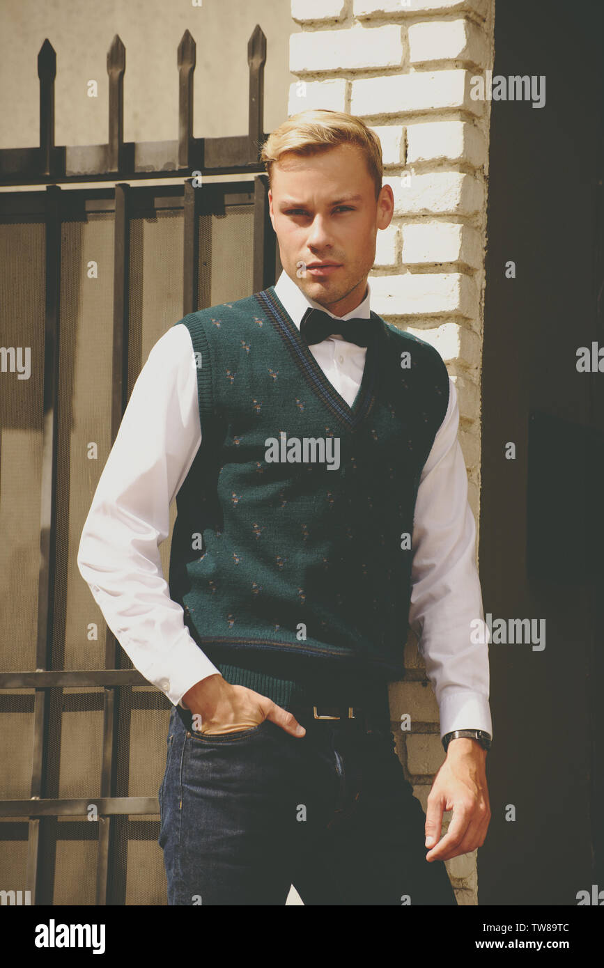 Homme caucasien portant un gilet et un noeud papillon posant. Il est blond et beau. Banque D'Images