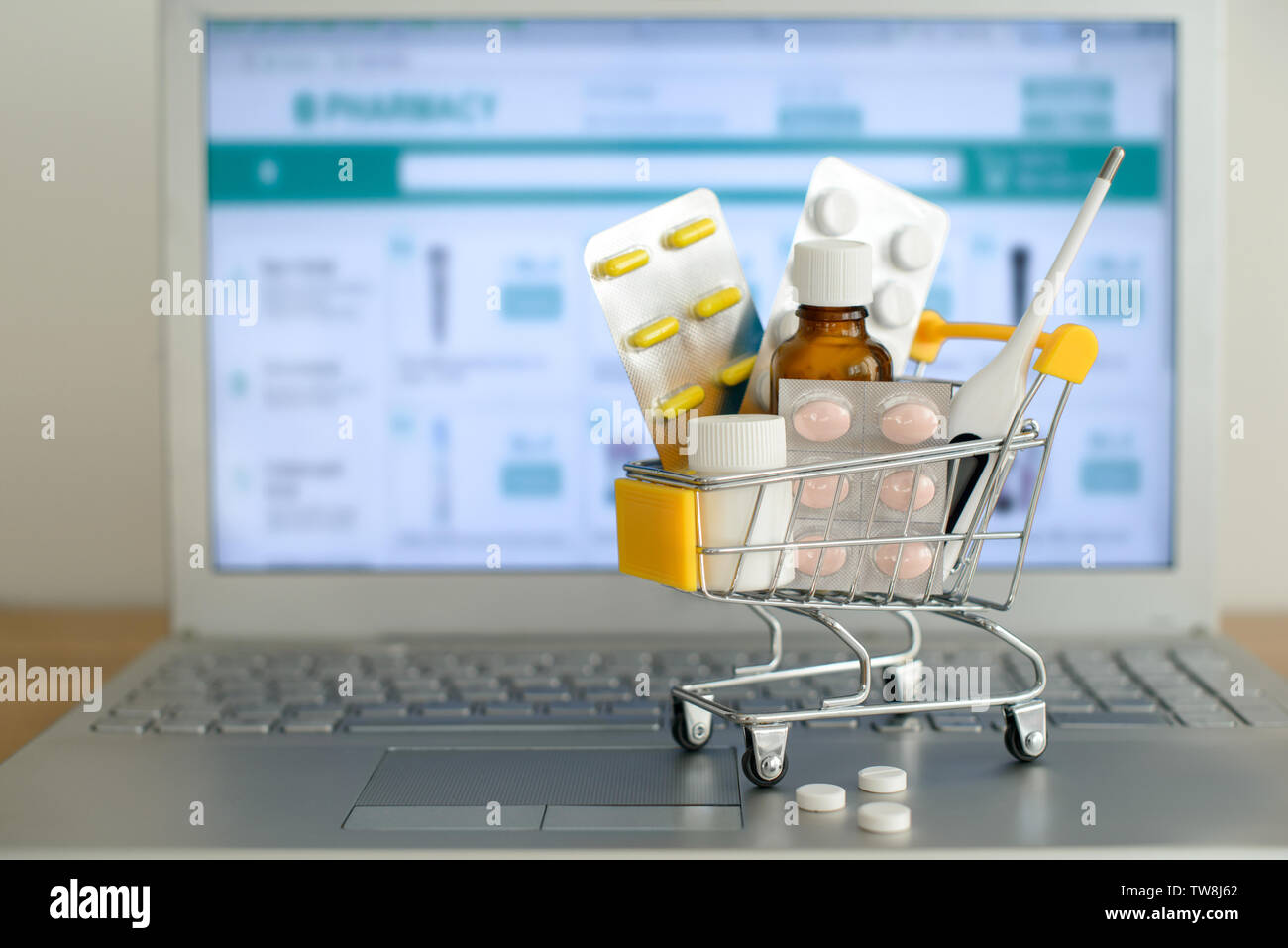 Panier jouet avec des médicaments devant un écran d'ordinateur portable avec pharmacie site web sur elle. Comprimés, blisters, flacons, thermomètre médical défini. Hea Banque D'Images