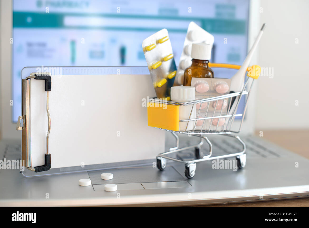 Panier jouet avec des médicaments et du papier remarque devant un écran d'ordinateur portable avec pharmacie site web sur elle. Comprimés, blisters, flacons médical, therm Banque D'Images