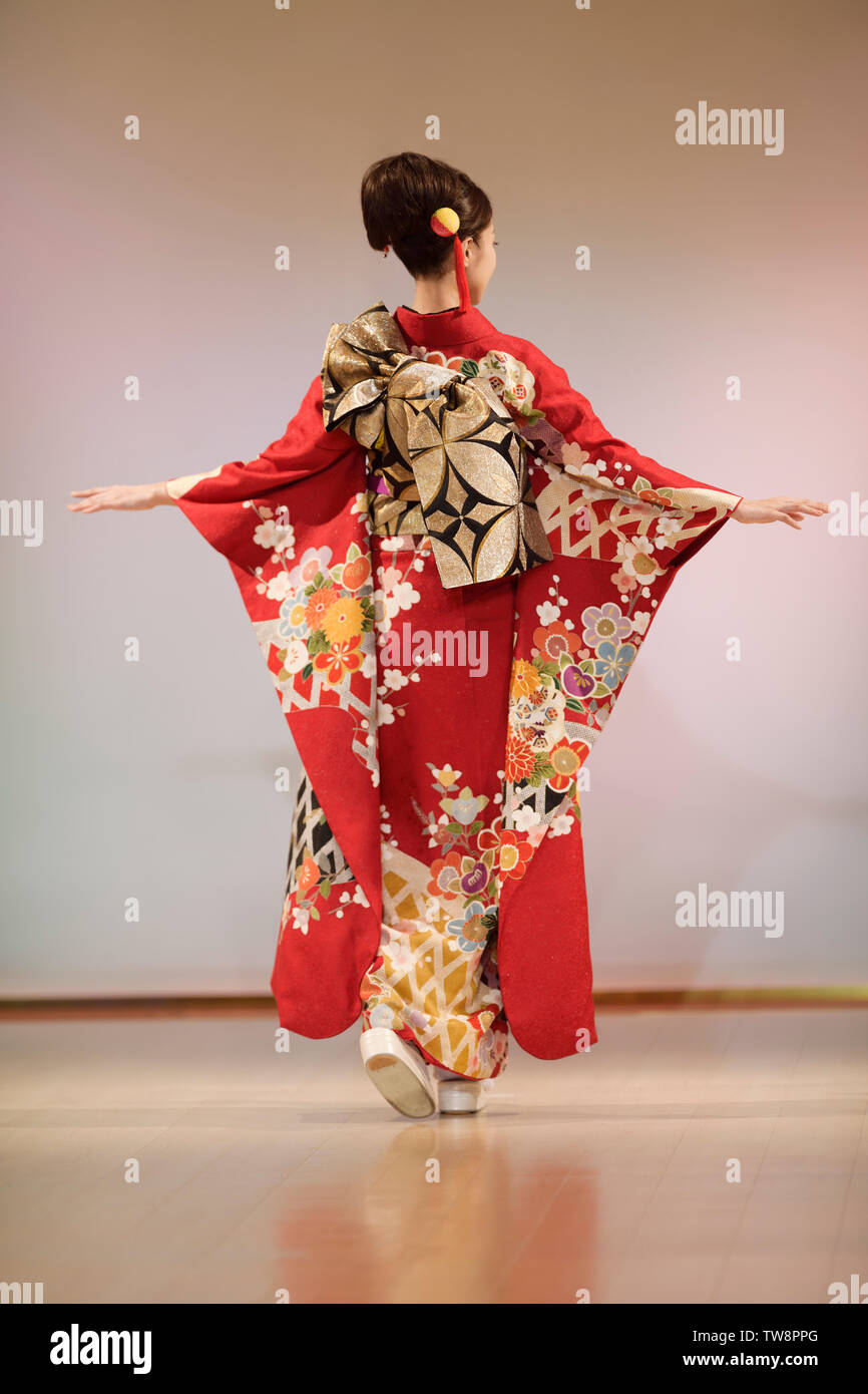 Femme japonaise dans un beau kimono rouge vif avec de longues manches et un  réseau complexe de ceinture obi or noeud sur son dos. Défilé de kimono à  Kyoto, au Japon Photo