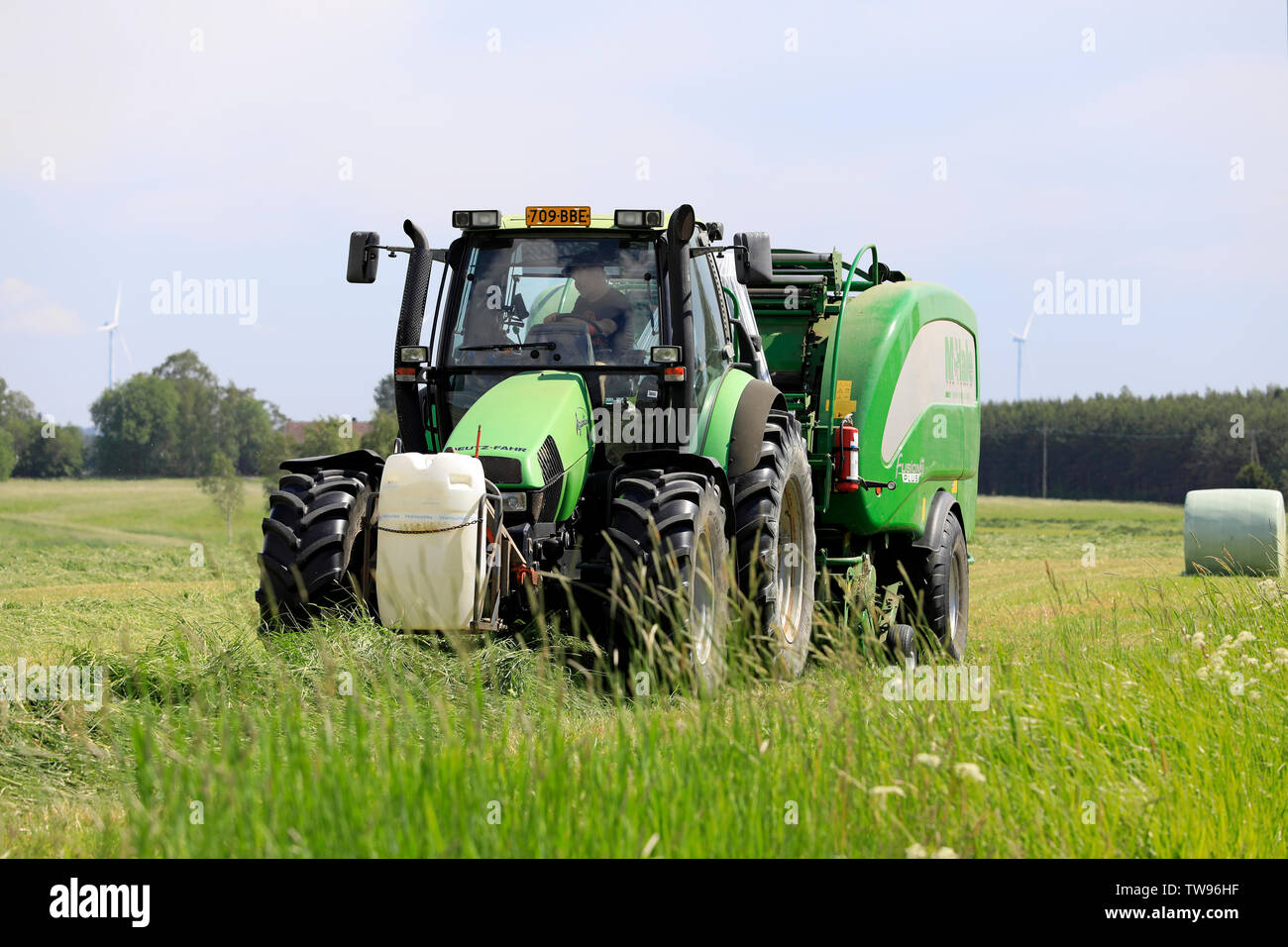 Salo, Finlande. Le 15 juin 2019. Exploitant agricole travaillant avec tracteur 1963 Chevrolet Suburban et McHale 3 plus enrubanneuse intégrée dans le champ de foin sur le jour de l'été Banque D'Images
