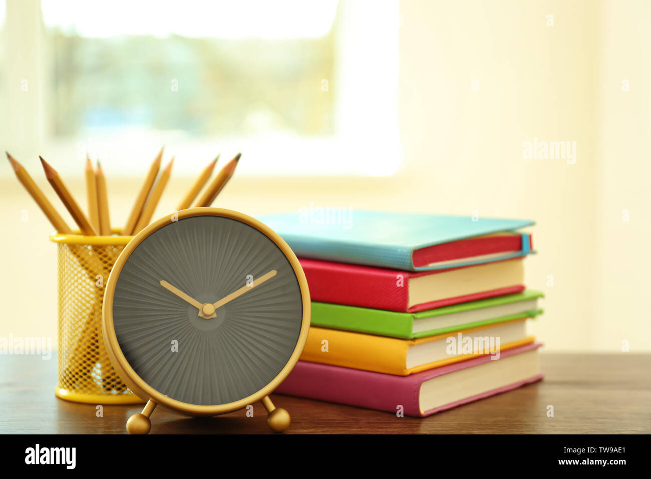 Réveil, papeterie et pile de livres sur la table. Le temps d'étudier Banque D'Images