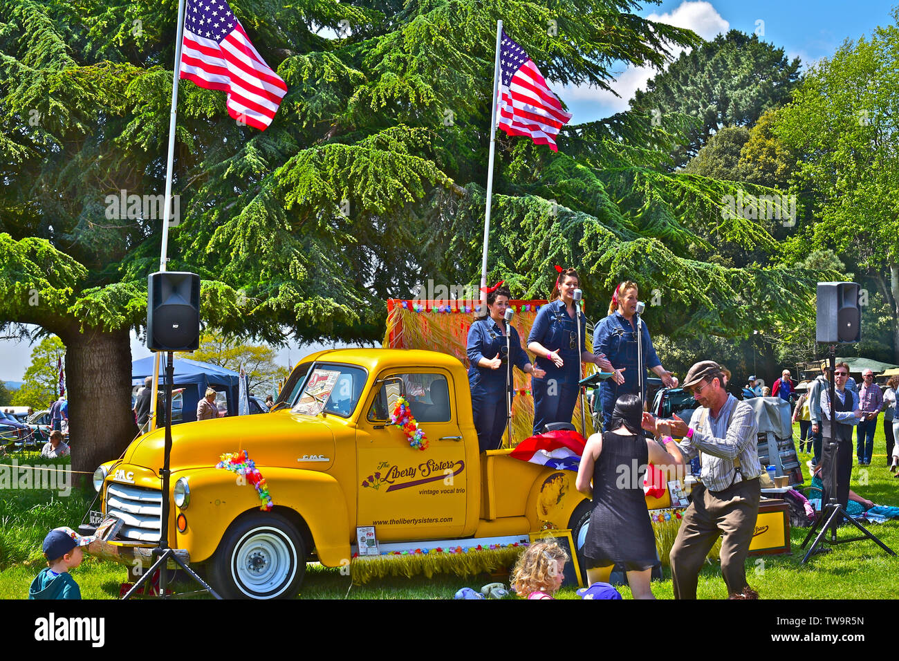 'La liberté Sisters' trio vocal effectuant de succès américains des années 20 s-30s à l'arrière de la dépanneuse GMC classique au Classic Car Show.Les gens danser/ regarder Banque D'Images
