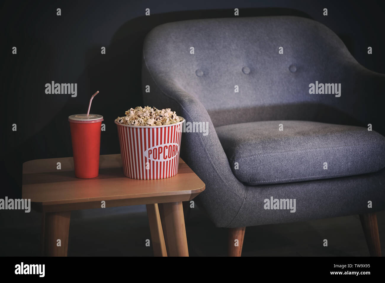 Table avec du maïs soufflé et des boissons près de fauteuil confortable à l'intérieur. Home cinema Banque D'Images