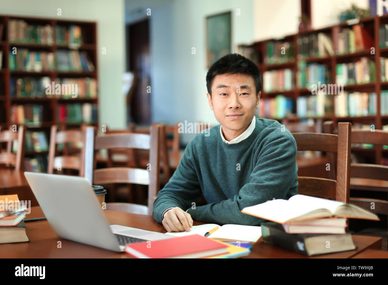 Asian student with laptop studying in library Banque D'Images