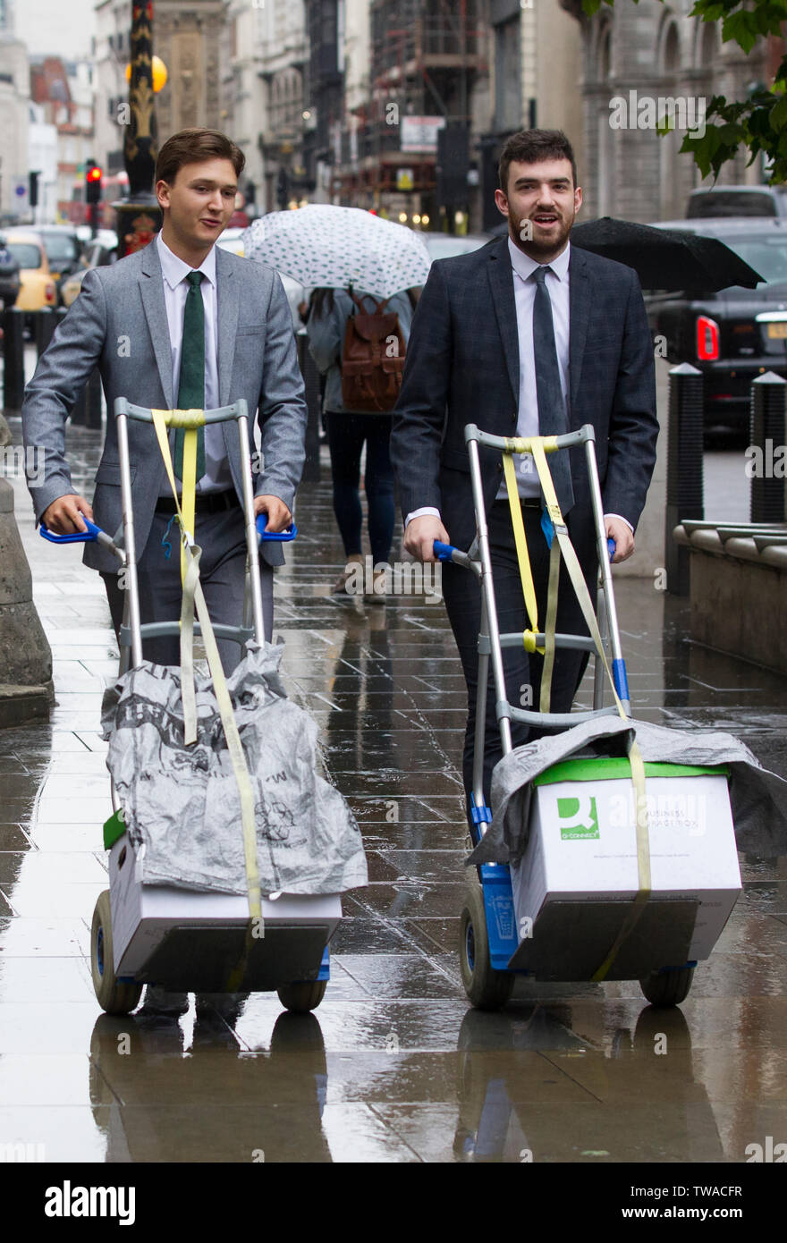 Procureurs greffiers chargés de boîtes de documents juridiques à l'extérieur de la Royal Courts of Justice, Strand, London, England, UK Banque D'Images