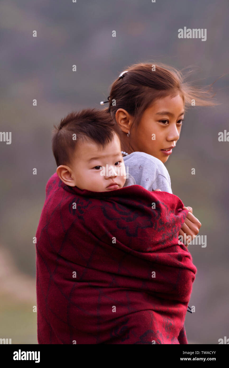 VILLAGE Khonoma, Nagaland, Inde, décembre 2016, jeune fille carryies Naga sœur sur son dos. Banque D'Images