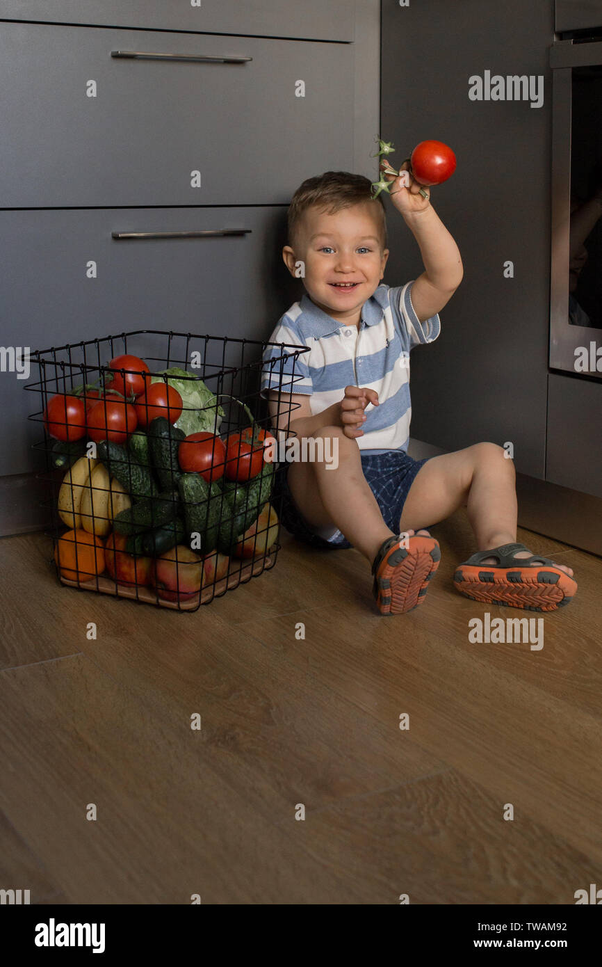 Petit enfant jouant avec des légumes frais dans la cuisine Banque D'Images