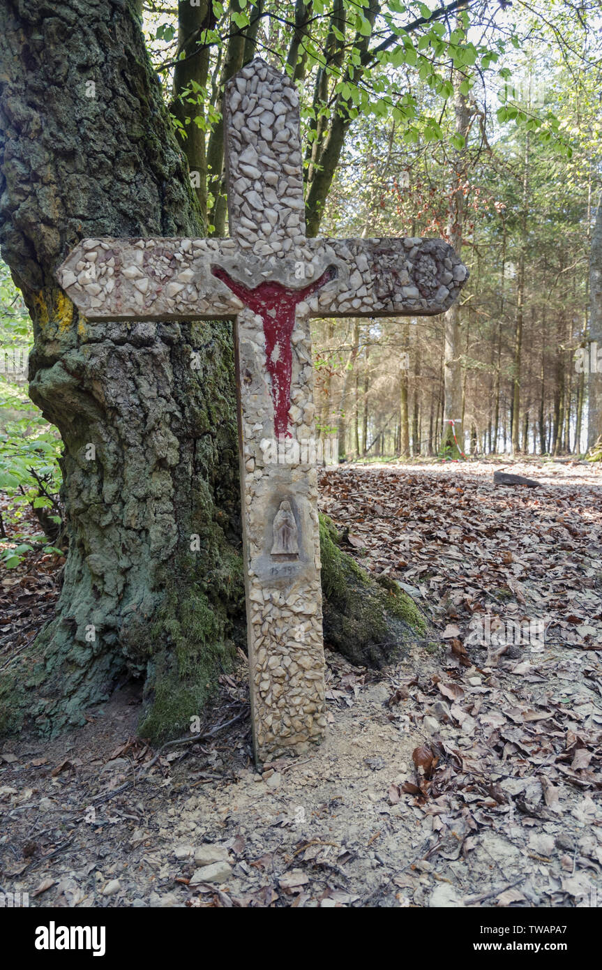 LA ROCHE-EN-ARDENNE, ardennes, BELGIQUE - 23 avril 2011 : une croix en pierre se trouve au pied d'un arbre dans les bois près de La Roche-en-ar Banque D'Images