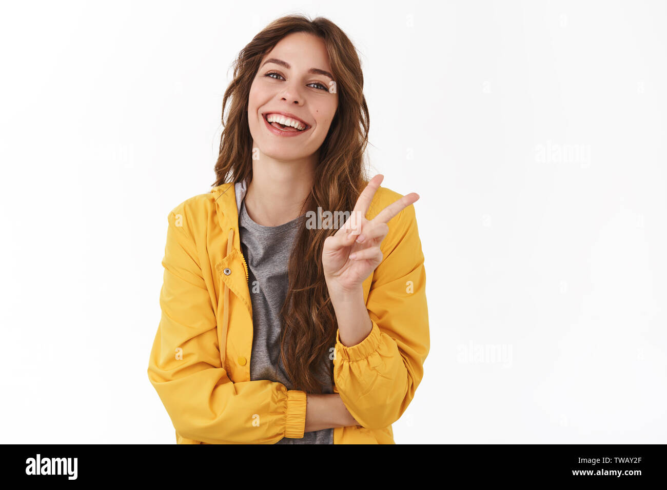 Les amis de la paix. Cheerful gorgeous girl enthousiaste chestnut curly hairstyle montrer geste victoire rire sourire optimiste Optimiste ayant sans souci Banque D'Images