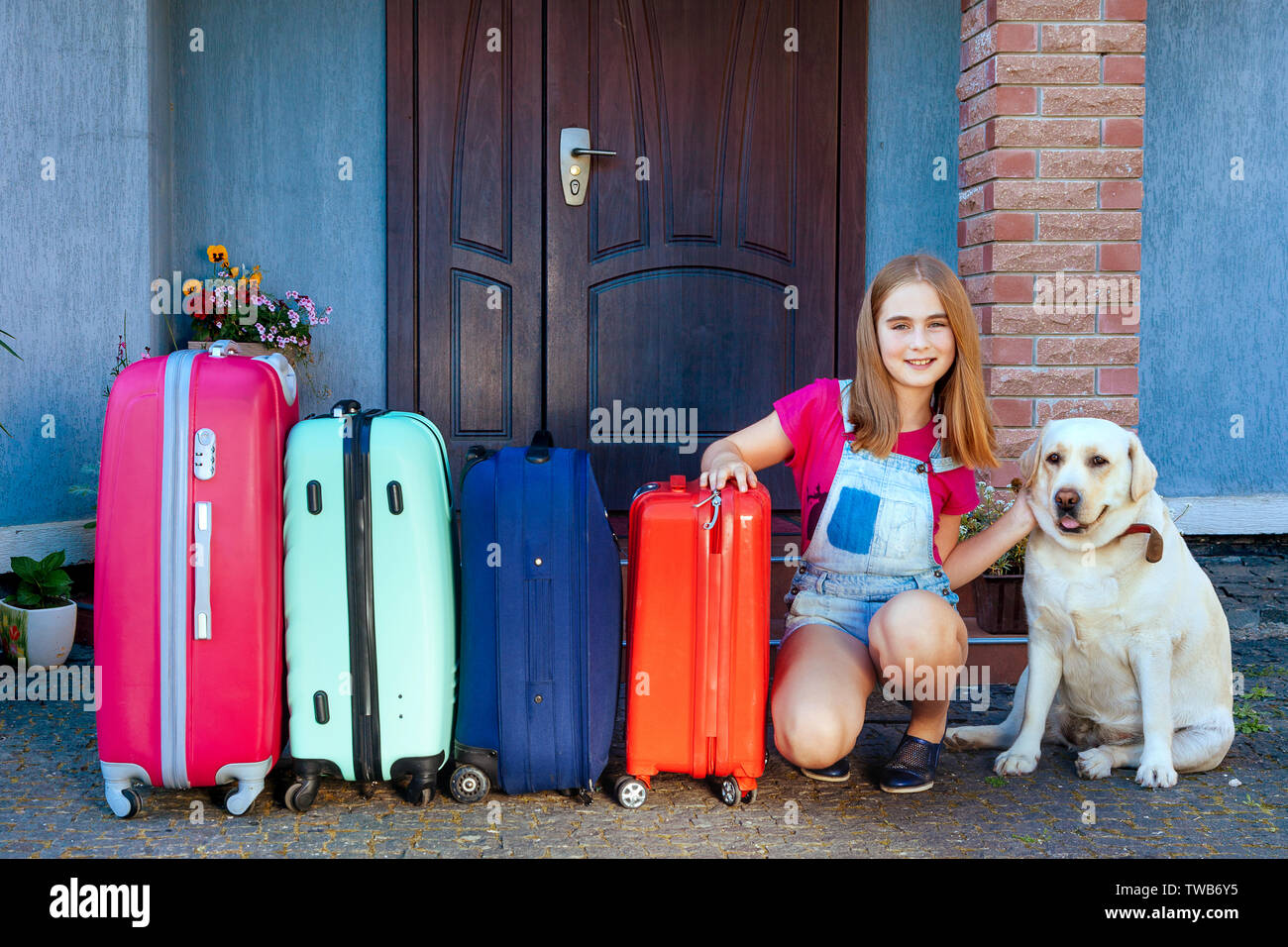 Une fille et un grand chien labrador près de valises multicolores. Prêt pour la famille pour les vacances d'été. Voyage de toute la famille avec un les Banque D'Images