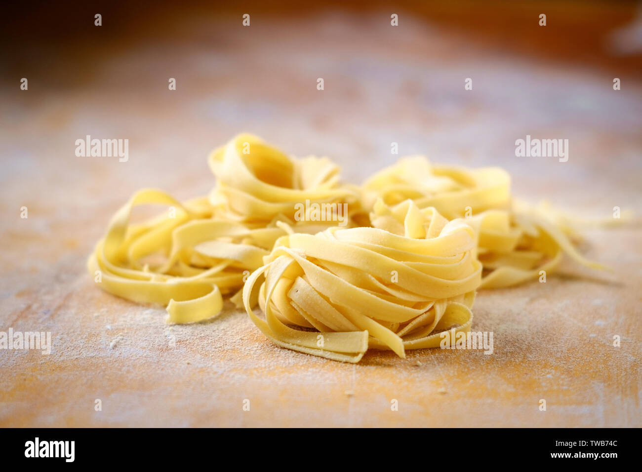 les pâtes fraîches de fettuccine nichent sur une table en bois avec de la farine Banque D'Images