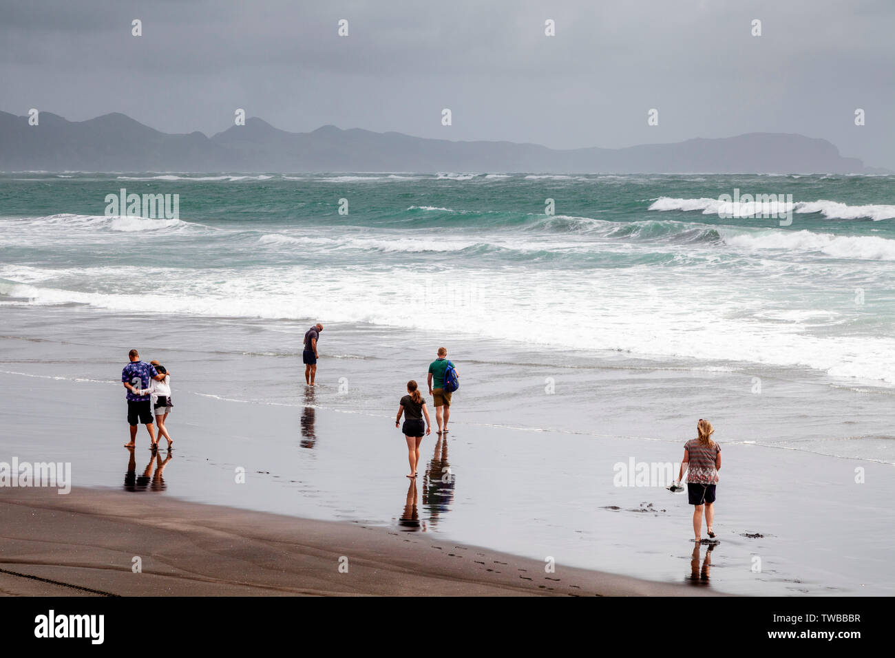 Un groupe de personnes à pied le long de Hot Water Beach (Plage), de l'océan, île du Nord Kawhia, Nouvelle-Zélande Banque D'Images