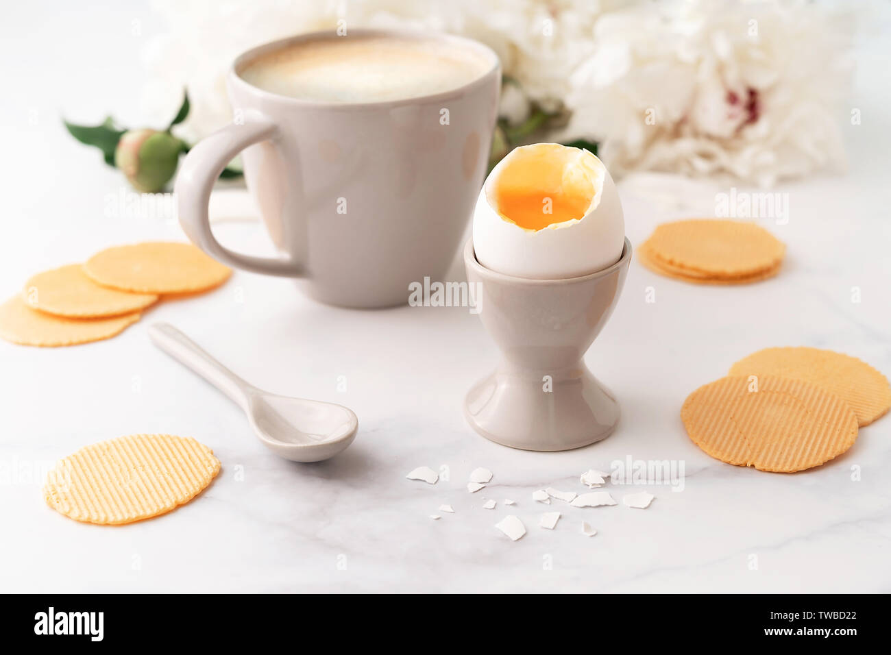 Oeufs à la coque avec liquide jaune orange en céramique egg cup, tasse de café avec cuillère en céramique mince et croustillante et les croustilles de maïs sur fond de belle wh Banque D'Images