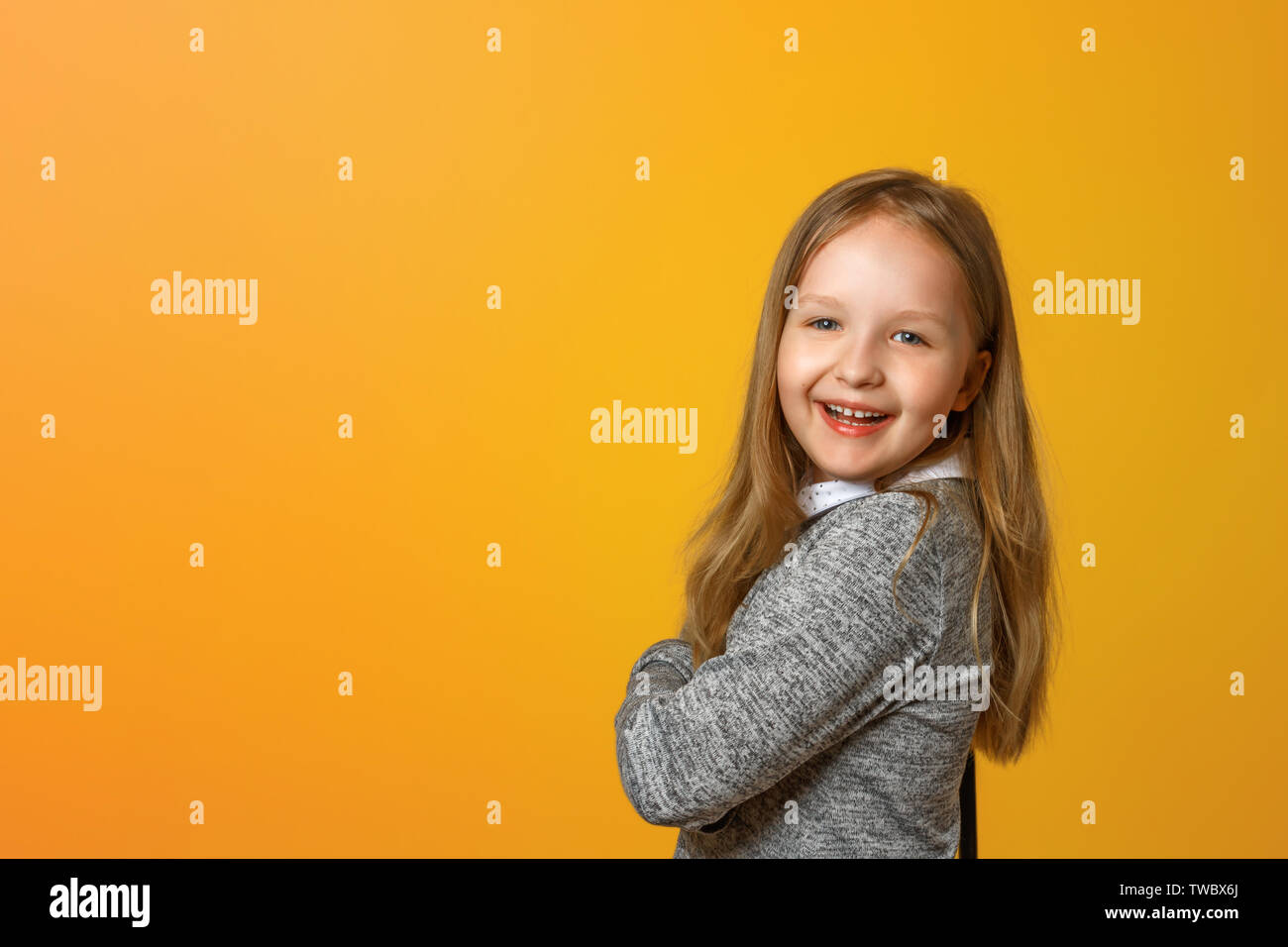 Portrait d'un drôle de petit fille blonde sur un fond jaune. Banque D'Images