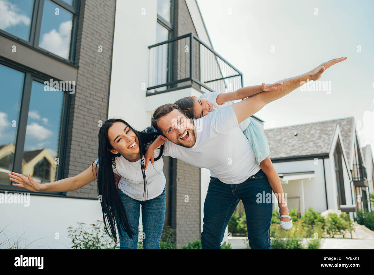 Fille sur un piggy back ride avec ses parents. Mère, père et fille ont un bon moment près de la chambre Banque D'Images