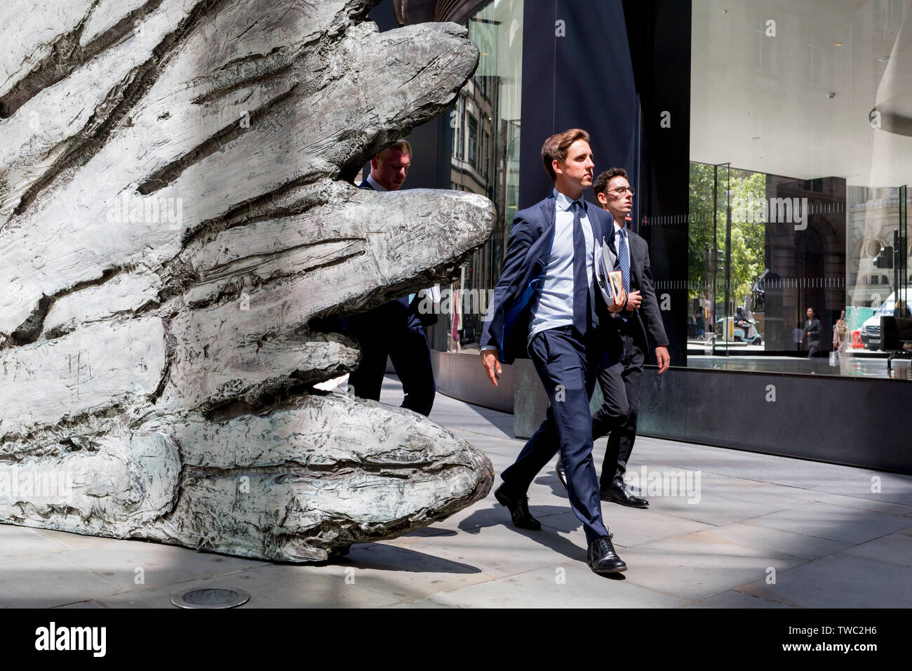 Les hommes d'affaires de la ville à pied au-delà de la sculpture intitulée 'ville' aile sur Threadneedle Street dans la ville de Londres, le quartier financier de la capitale, le 17 juin 2019, à Londres, en Angleterre. Cette dix mètres de haut est la sculpture en bronze par le président de la Royal Academy of Arts, Christopher Le Brun, commandé par Hammerson en 2009. 'La Ville' de l'aile et a été jeté par Morris Singer, fondateurs de l'art réputé pour être la plus ancienne fonderie d'art dans le monde. Banque D'Images