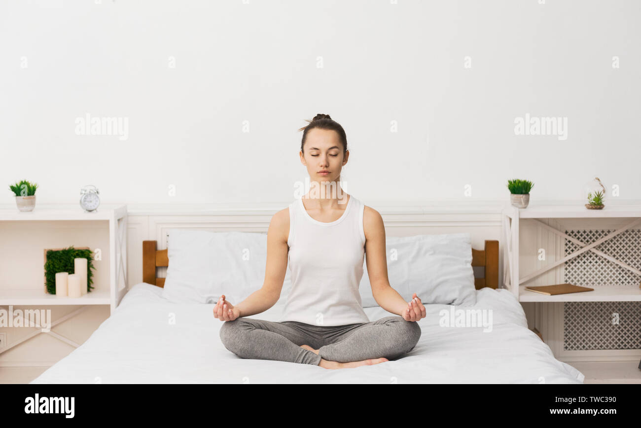 Concept de méditation. Woman Practicing Yoga On lit, le réveil le matin Banque D'Images