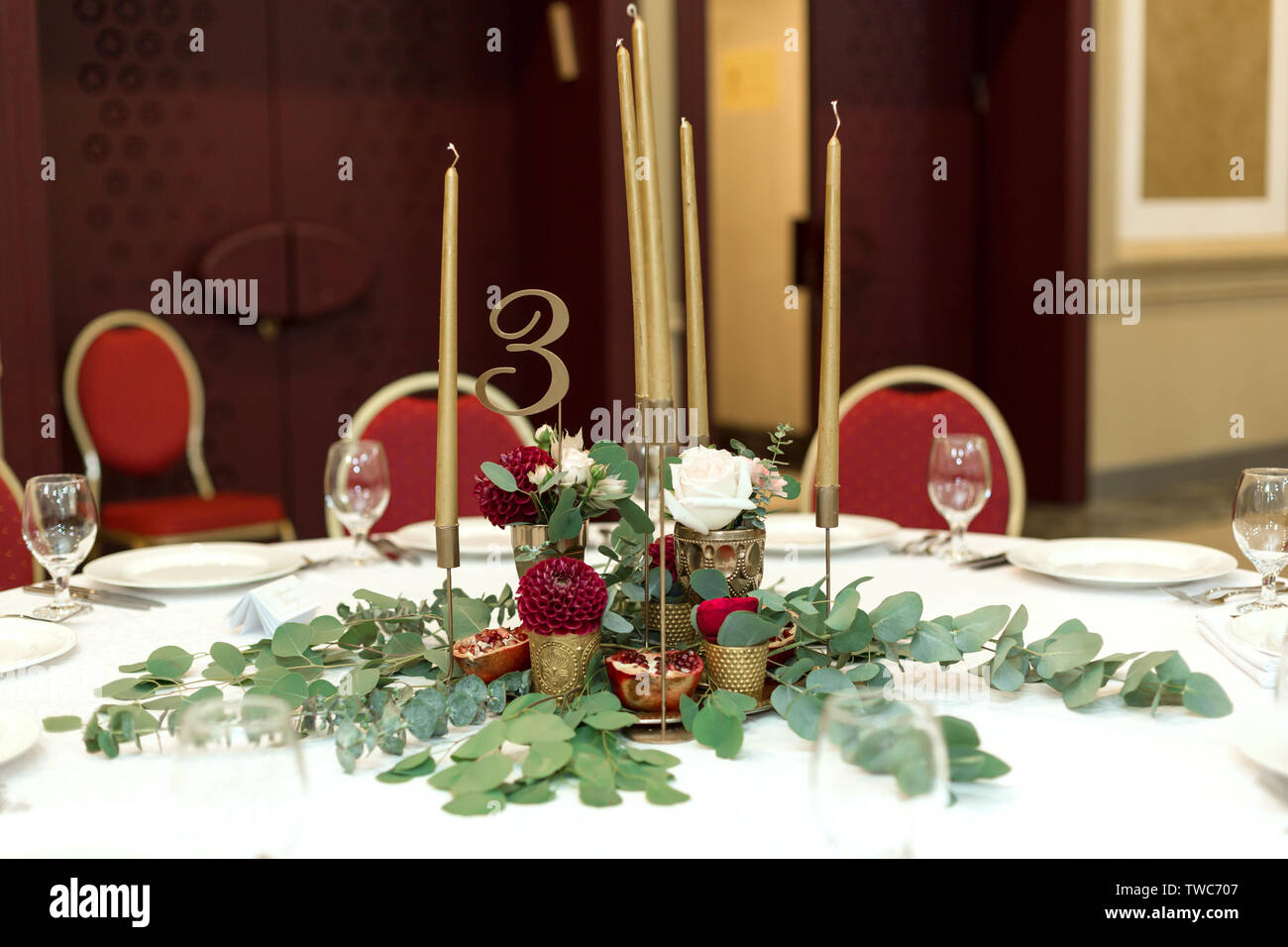 Décoration de fête banquet ronde table dans le restaurant. Les fleurs fraîches sont d'or bougies et des chaises rouges. Cher riches. Banque D'Images