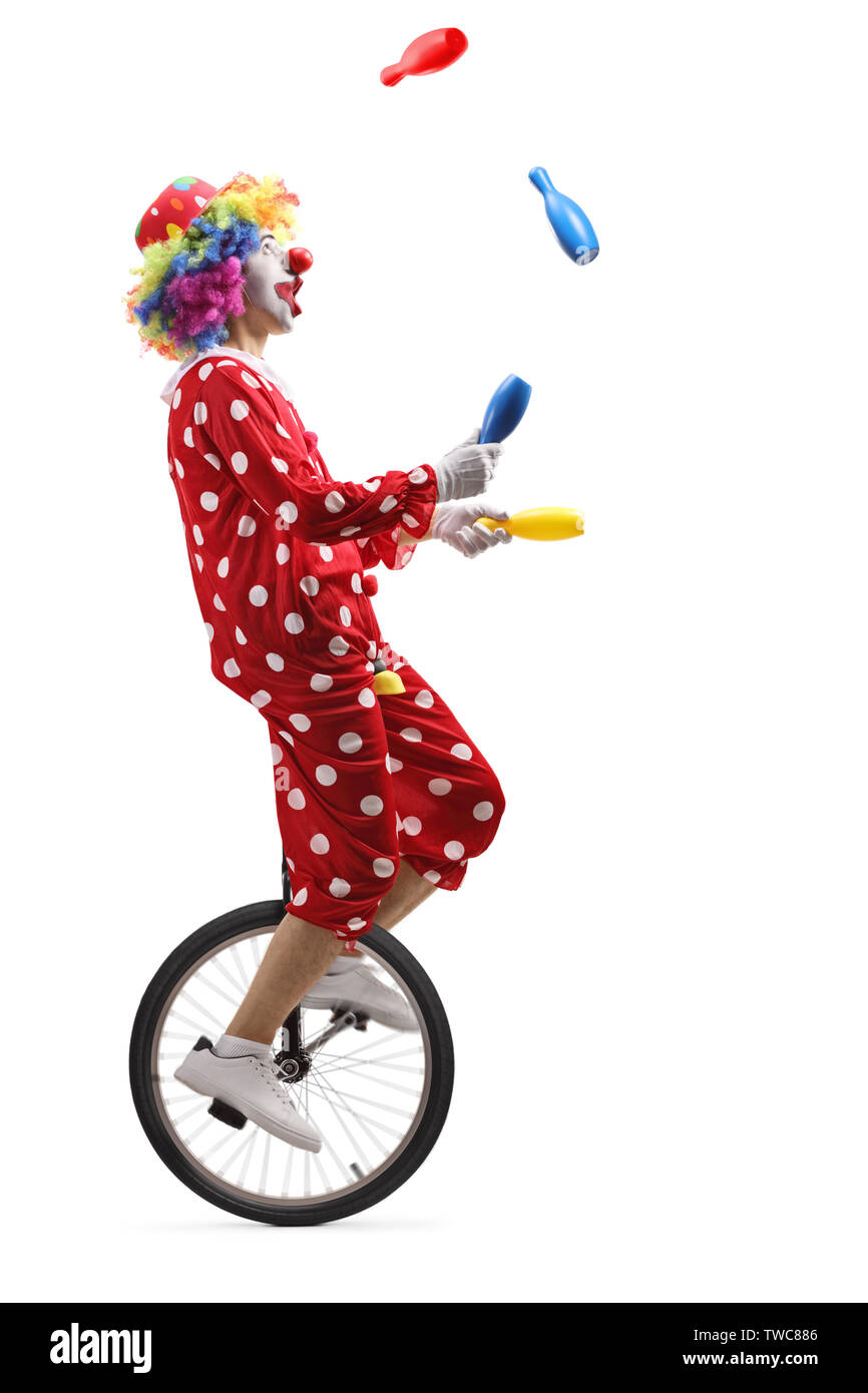 De toute la longueur d'un clown sur un monocycle jonglage avec les clubs isolé sur fond blanc Banque D'Images